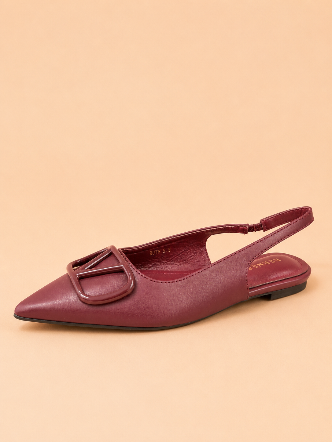 Maroon flat shoe with a slingback design on a beige background